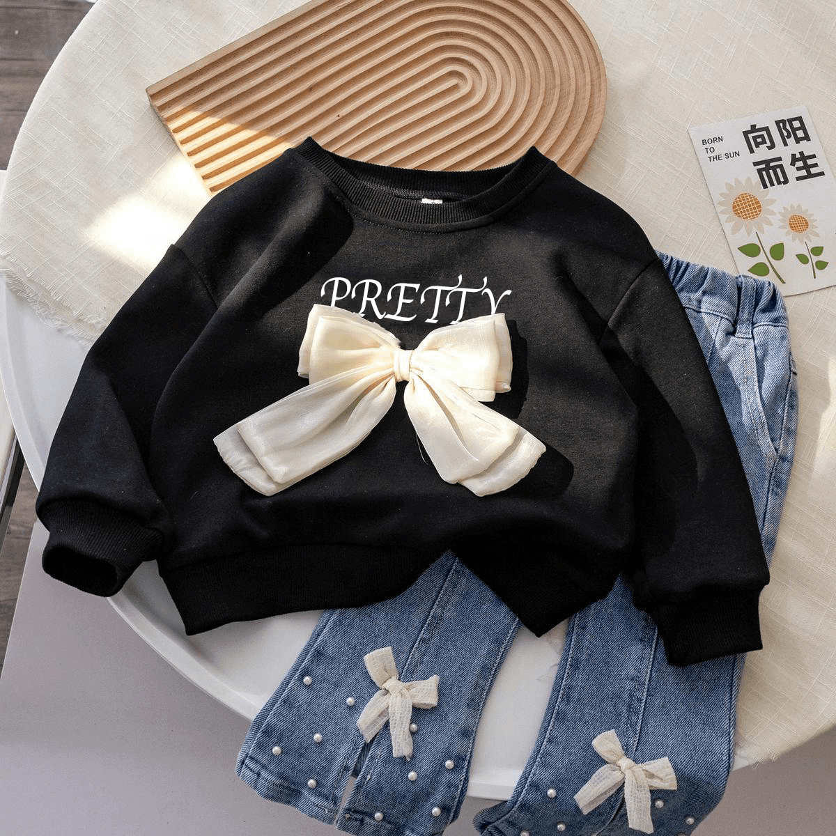 Stylish girls outfit with a modern touch - black top with stylish bowknot and attractive pleated jeans - IRRAKIDS