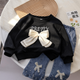 Stylish girls outfit with a modern touch - black top with stylish bowknot and attractive pleated jeans
